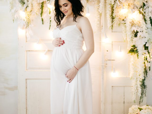 Couple of handsome husband and pretty pragnant woman posing at studio