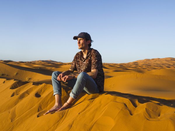 man-sitting-top-dune-desert