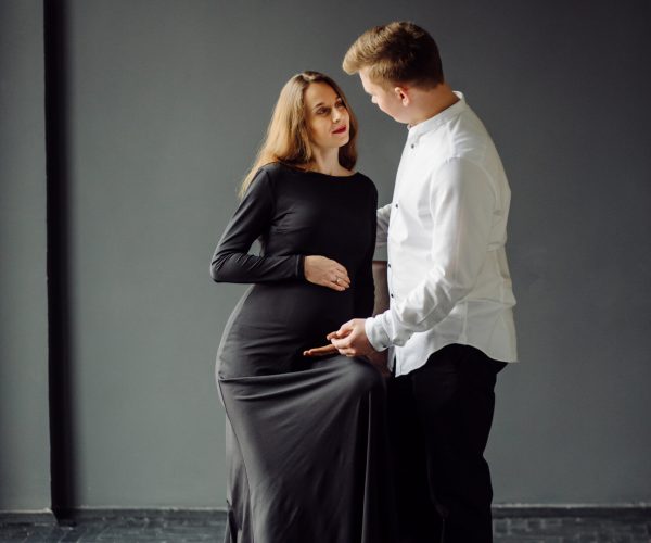 Man in white shirt and female in black dress. Pregnancy photo