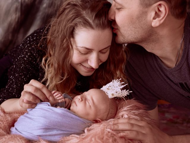 The mother and father sitting near  their daughter