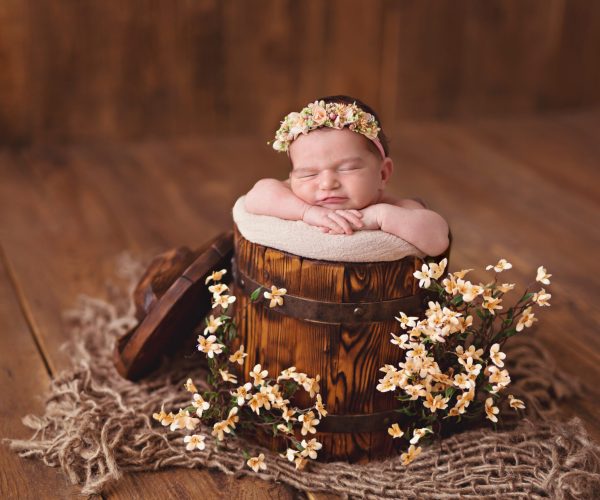 Newborn girl, baby sleeps in a bucket of flowers.