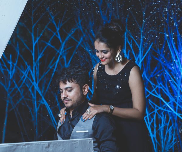 young-couple-looking-camera-night-against-blue-bushy-background